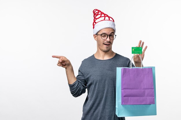 Vooraanzicht van jonge man met cadeautjes en bankkaart op witte muur