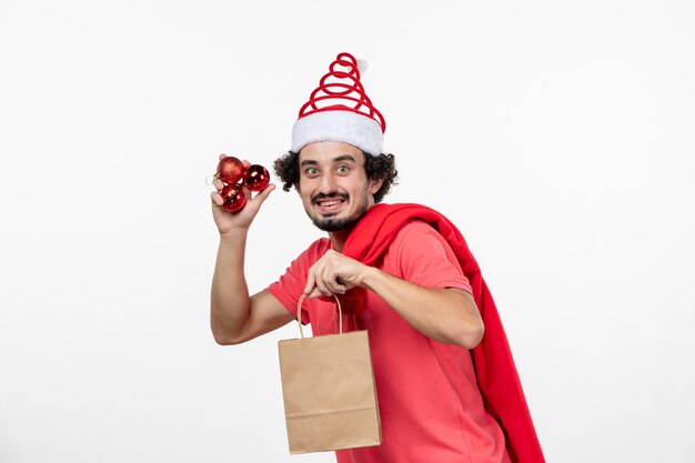 Vooraanzicht van jonge man met cadeautjes en speelgoed op witte muur