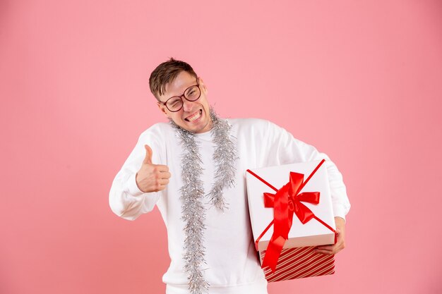 Vooraanzicht van jonge man met kerstcadeau op de roze muur