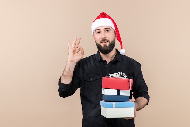 Vooraanzicht van jonge man met kerstcadeautjes op de roze muur