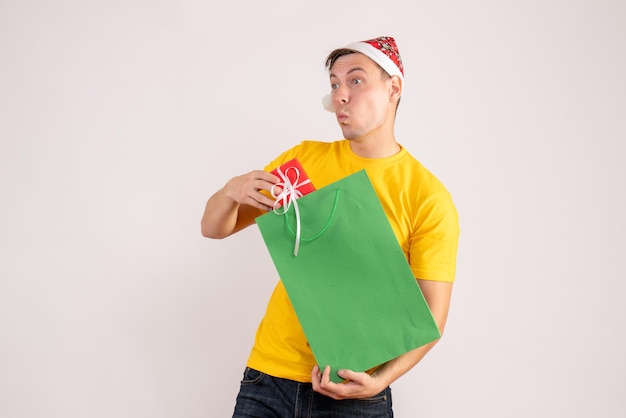 Gratis foto vooraanzicht van jonge man met pakket en klein cadeautje op witte muur