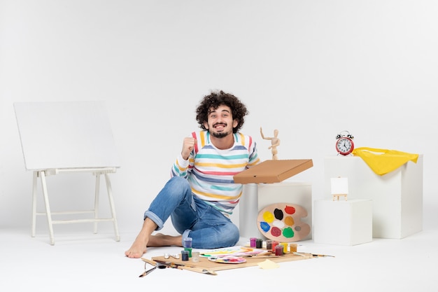 Gratis foto vooraanzicht van jonge man met pizzadoos op witte muur