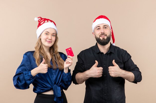 Gratis foto vooraanzicht van jonge man met vrouw die bankkaart op de roze muur houdt