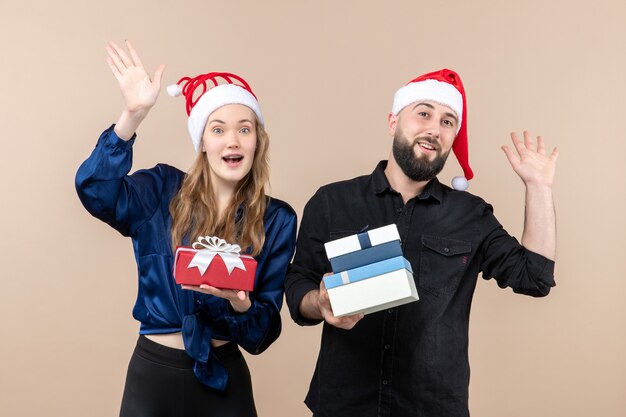 Vooraanzicht van jonge man met vrouw met cadeautjes op roze muur