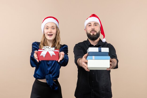 Vooraanzicht van jonge man met vrouw met cadeautjes op roze muur