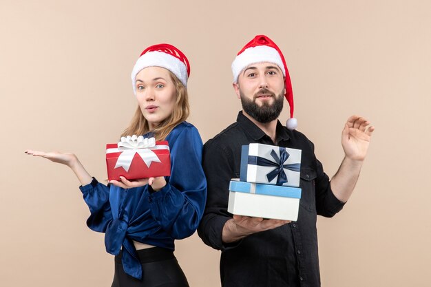 Vooraanzicht van jonge man met vrouw met cadeautjes op roze muur