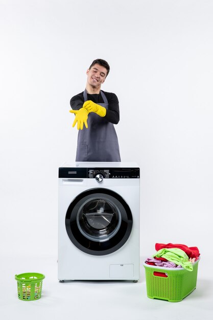 Vooraanzicht van jonge man met wasmachine en vuile kleren op witte muur