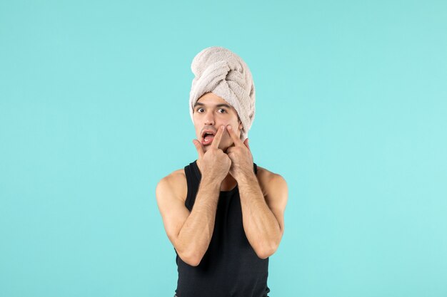 vooraanzicht van jonge man na het douchen met handdoek op zijn hoofd op blauwe muur