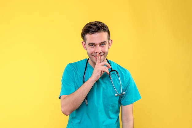 Vooraanzicht van jonge mannelijke arts die op gele muur glimlacht