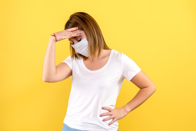 Vooraanzicht van jonge vrouw beklemtoond in masker op gele muur