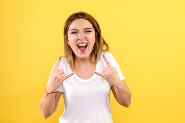 Vooraanzicht van jonge vrouw die emotioneel op gele muur verheugt