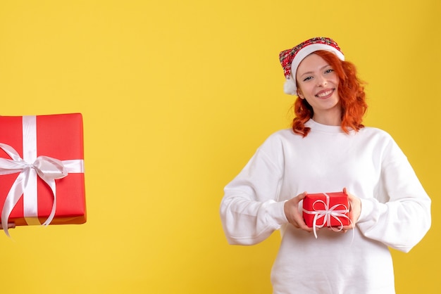 Vooraanzicht van jonge vrouw die kleine kerstmis op een gele muur houdt