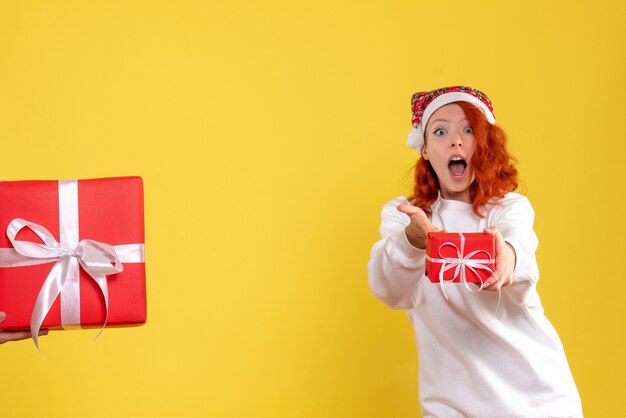 Vooraanzicht van jonge vrouw die kleine Kerstmis op een gele muur houdt