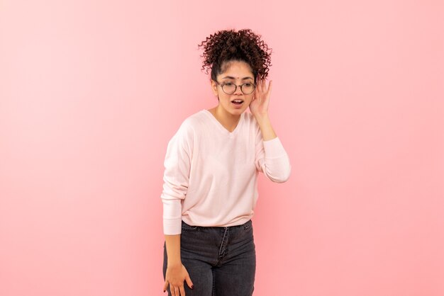 Vooraanzicht van jonge vrouw die nauw luistert op roze muur