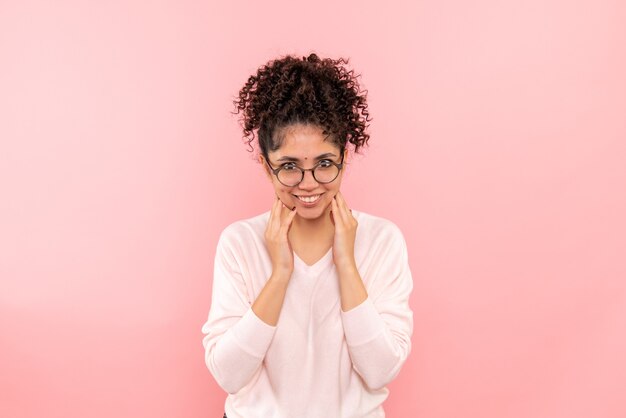 Vooraanzicht van jonge vrouw die op de roze muur glimlacht