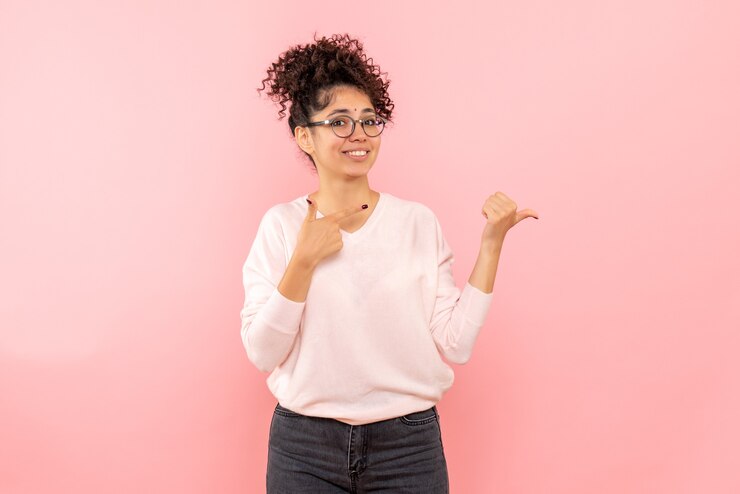 Gratis Foto vooraanzicht van jonge vrouw die op de roze muur glimlacht