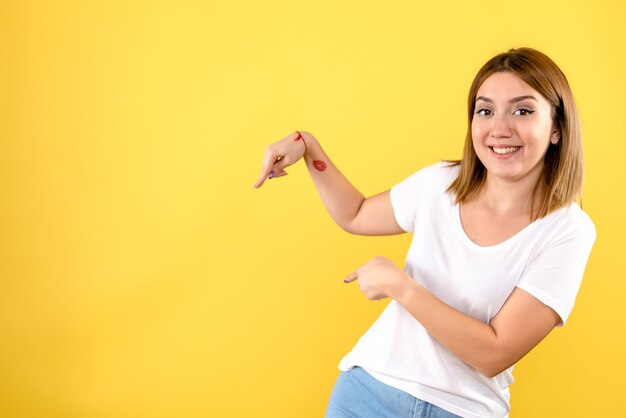 Vooraanzicht van jonge vrouw die op gele muur glimlacht