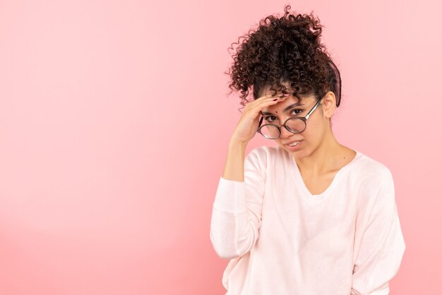 Vooraanzicht van jonge vrouw die op roze muur denkt