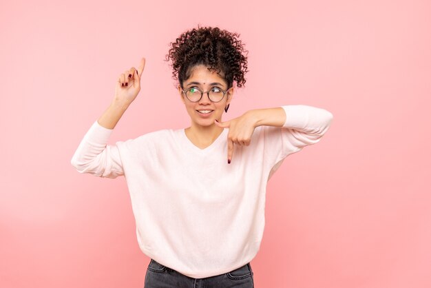 Vooraanzicht van jonge vrouw die op roze muur denkt