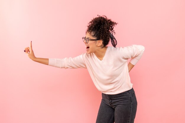 Vooraanzicht van jonge vrouw die op roze muur gilt