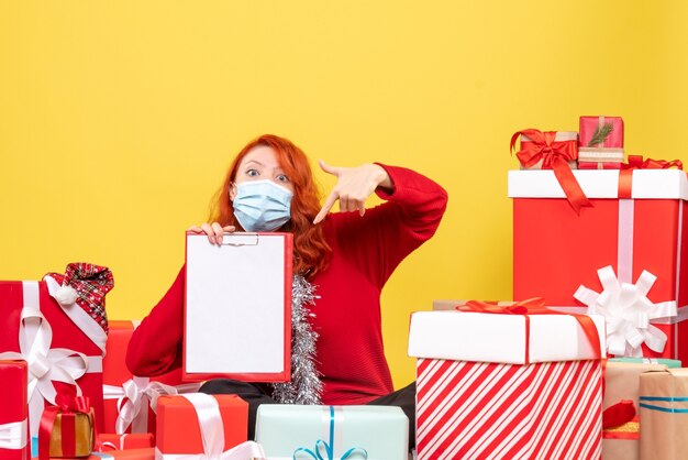 Vooraanzicht van jonge vrouw die rondhangen stelt in masker met dossiernota op gele muur voor