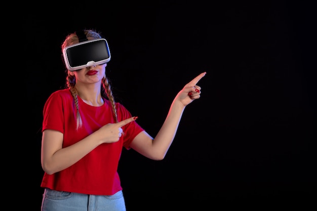 Vooraanzicht van jonge vrouw die vr op donkere muur speelt