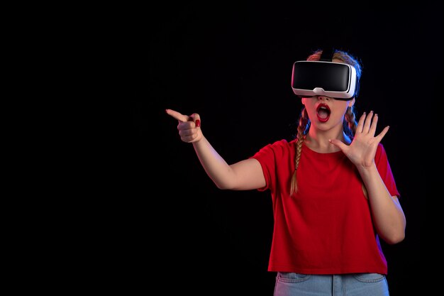 Vooraanzicht van jonge vrouw die vr op donkere muur speelt