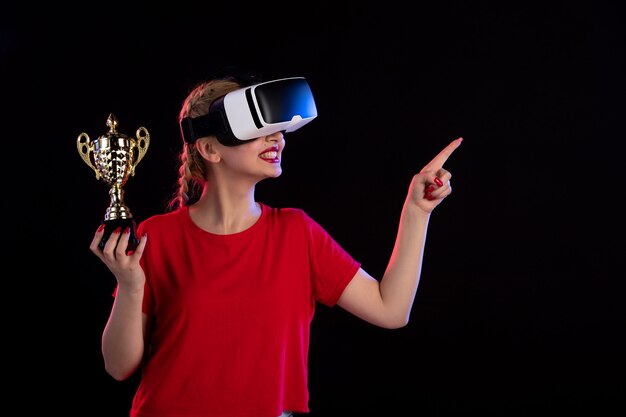 Vooraanzicht van jonge vrouw die vr speelt en beker wint op donkere game visuele d