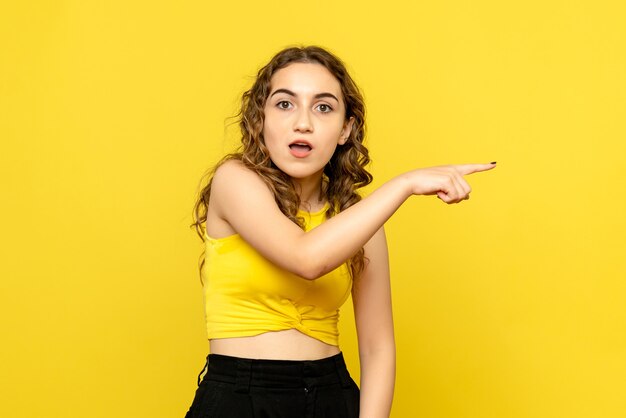 Vooraanzicht van jonge vrouw die zich gewoon op gele muur bevindt