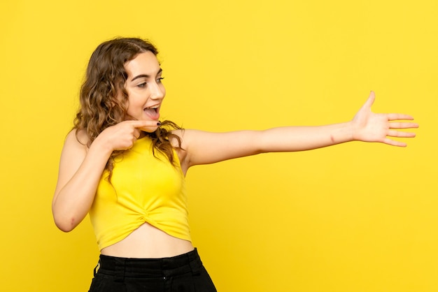 Gratis foto vooraanzicht van jonge vrouw die zich op gele muur verheugt