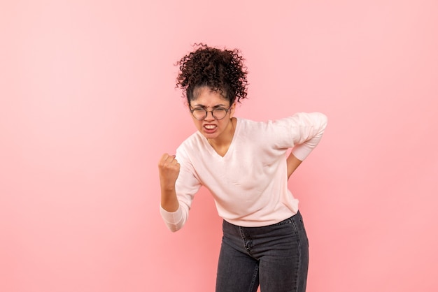 Vooraanzicht van jonge vrouw die zich op roze muur verheugt