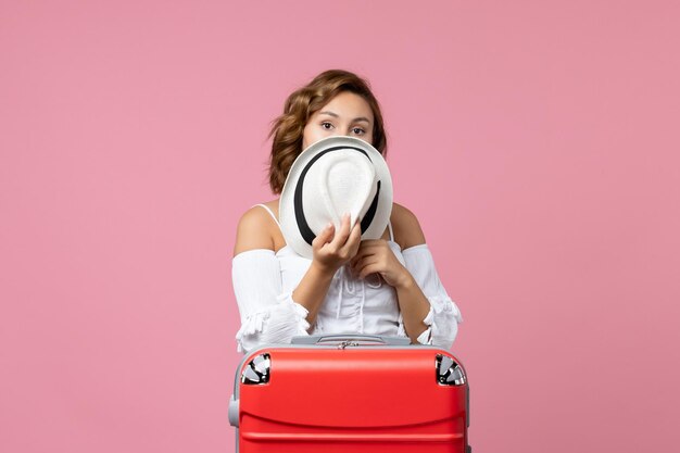 Vooraanzicht van jonge vrouw die zich voorbereidt op vakantie met rode tas die zich voordeed op de roze muur