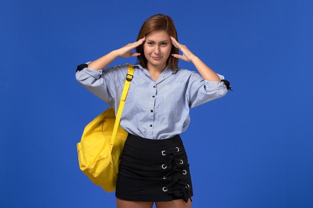 Vooraanzicht van jonge vrouw in blauw shirt met gele rugzak poseren