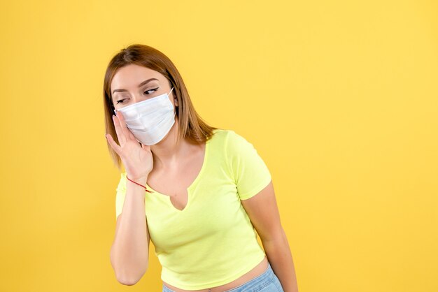 Vooraanzicht van jonge vrouw in masker op gele muur