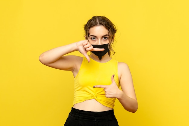 Vooraanzicht van jonge vrouw in masker op gele muur