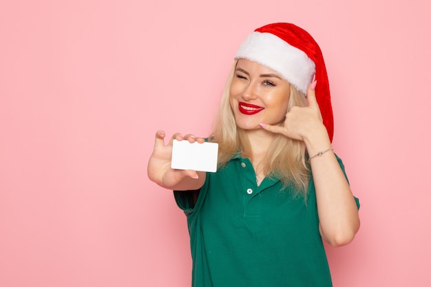 Vooraanzicht van jonge vrouw in rode dop met witte kaart op de roze muur