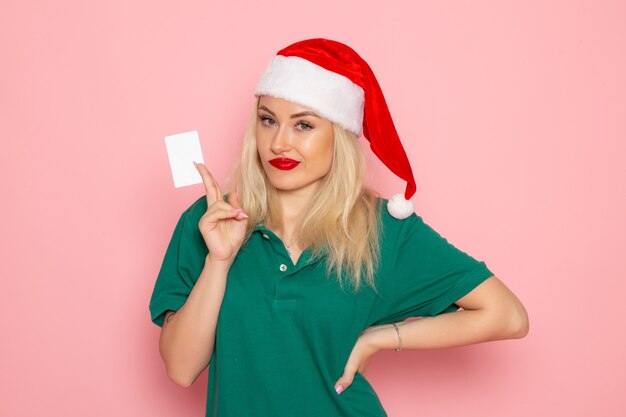 Vooraanzicht van jonge vrouw in rode dop met witte kaart op de roze muur