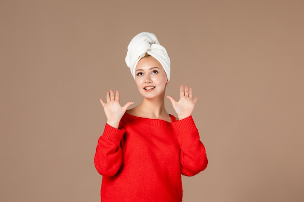 Vooraanzicht van jonge vrouw in rood shirt met handdoek op haar hoofd bruine muur
