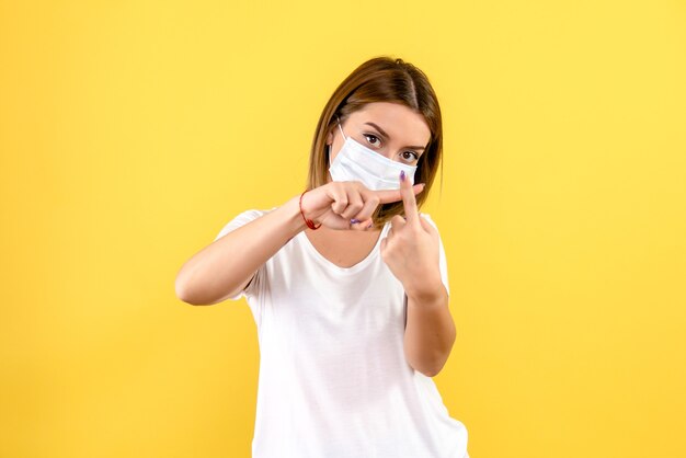 Vooraanzicht van jonge vrouw in steriel masker op gele muur