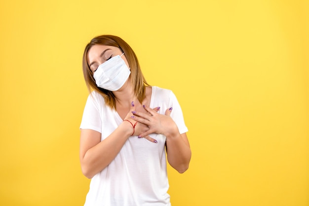 Vooraanzicht van jonge vrouw in steriel masker op gele muur