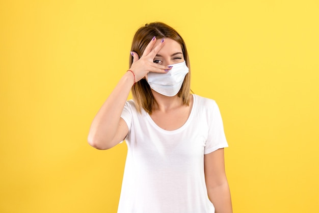 Vooraanzicht van jonge vrouw in steriel masker op gele muur