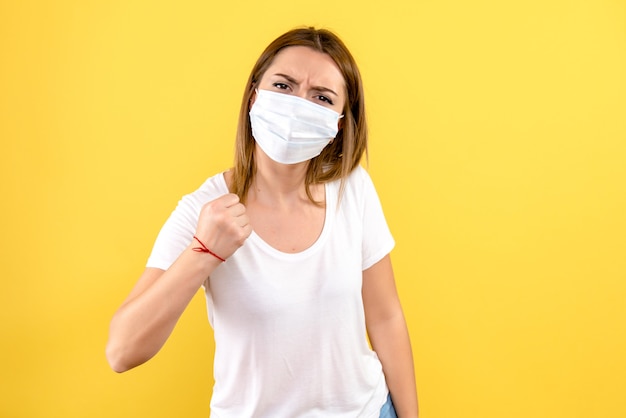 Vooraanzicht van jonge vrouw in steriel masker op gele muur