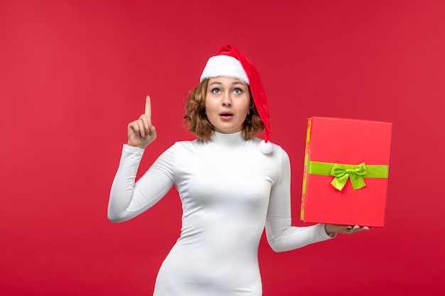Gratis foto vooraanzicht van jonge vrouw met cadeau op rood