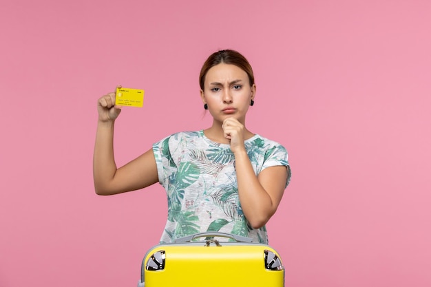 Vooraanzicht van jonge vrouw met gele bankkaart op de roze muur