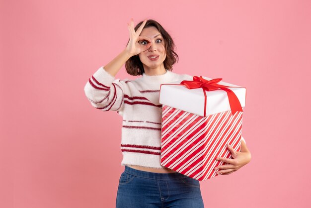 Vooraanzicht van jonge vrouw met kerstcadeau op de roze muur