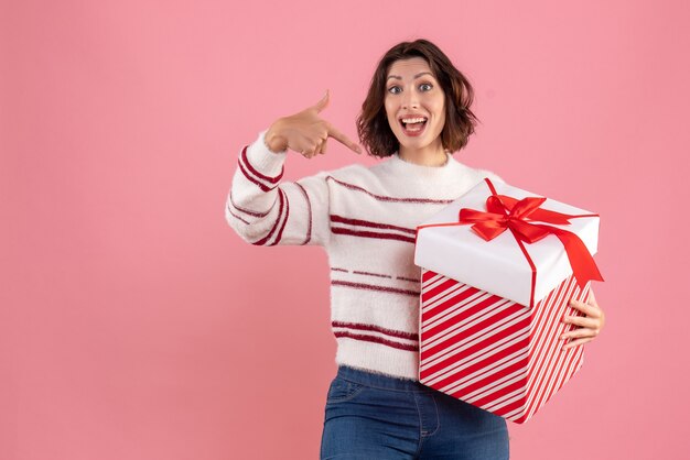 Vooraanzicht van jonge vrouw met kerstcadeau op de roze muur