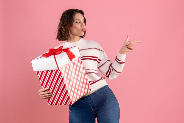 Vooraanzicht van jonge vrouw met kerstcadeau op de roze muur