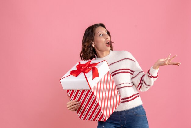 Vooraanzicht van jonge vrouw met kerstcadeau op de roze muur