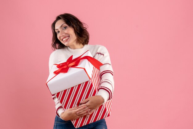 Vooraanzicht van jonge vrouw met kerstcadeau op de roze muur