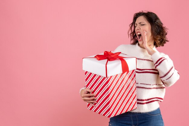 Vooraanzicht van jonge vrouw met kerstcadeau op de roze muur